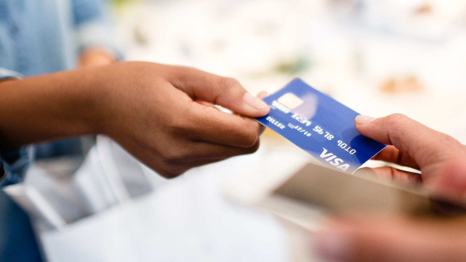 Woman handing Visa card to clerk for purchase.