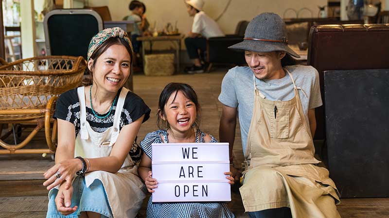 A family sitting and holding a sign, representing a local small business.